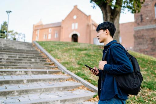 大学の構内を歩く男子大学生 大学の構内を歩く男子大学生の写真