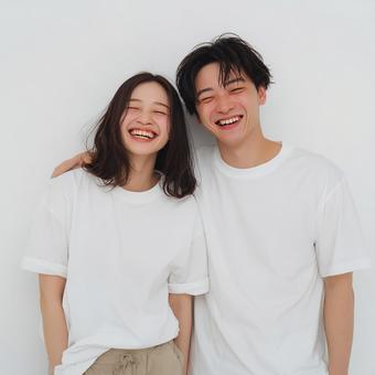 白壁に寄り添う若いカップルの写真