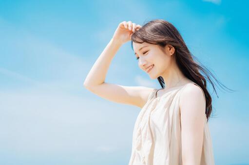 青空背景の若い女性 女性,脱毛,スキンケアの写真素材