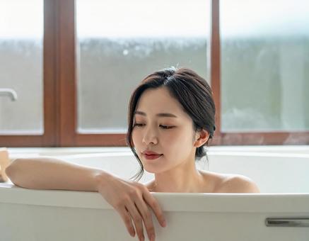 バスタイムに浴槽でリラックスする女性 バスタイムに浴槽でリラックスする女性の写真