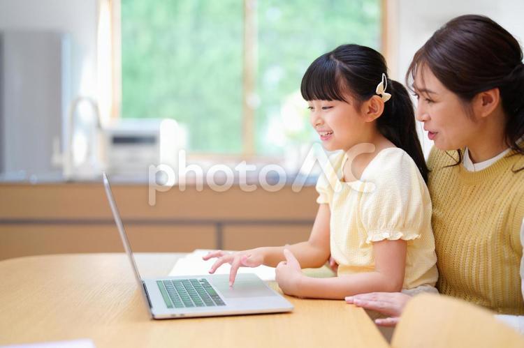 パソコンを操作する娘と笑顔の母 母,娘,ノートパソコンの写真素材