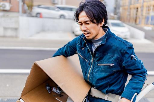 工事現場からエアコンの廃材を運ぶ作業員 工事現場からエアコンの廃材を運ぶ作業員 工事,廃材,ゴミの写真素材