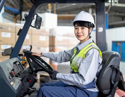 フォークリフトを運転する女性作業員 フォークリフトを運転する女性作業員の写真
