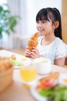 両手にクロワッサンを持つ笑顔の女の子 女の子,食事,クロワッサンの写真素材