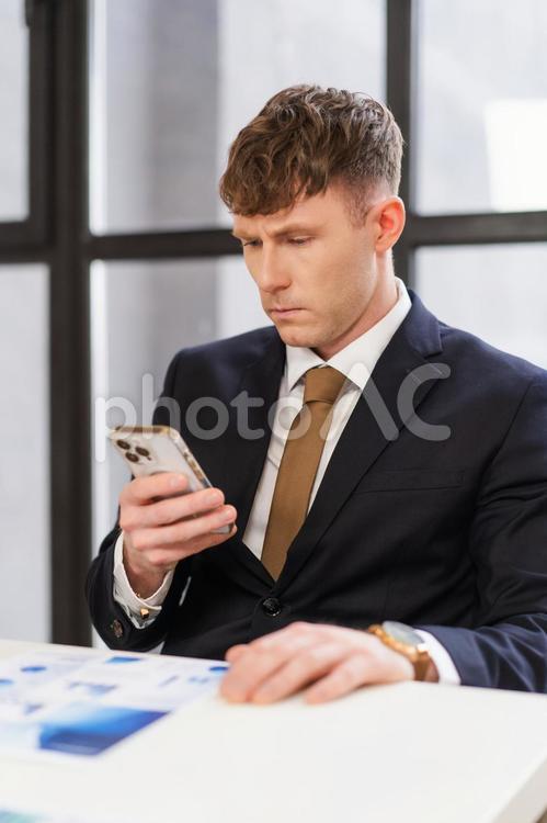 窓際の席でスマホを見ている男性 男性,スマートフォン,持つの写真素材