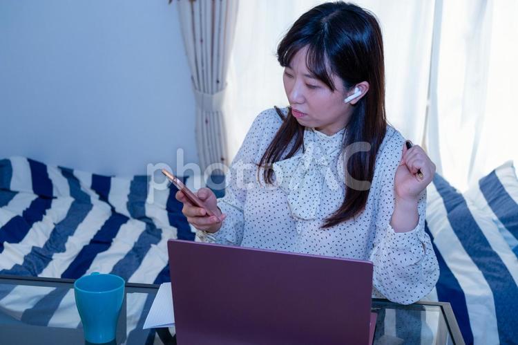 画面の同僚と話しながら真面目にリモートワークをする女性 日本人,家,仕事の写真素材