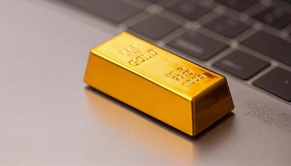 パソコンに置かれた金の延べ棒のミニチュア パソコンに置かれた金の延べ棒のミニチュアの写真