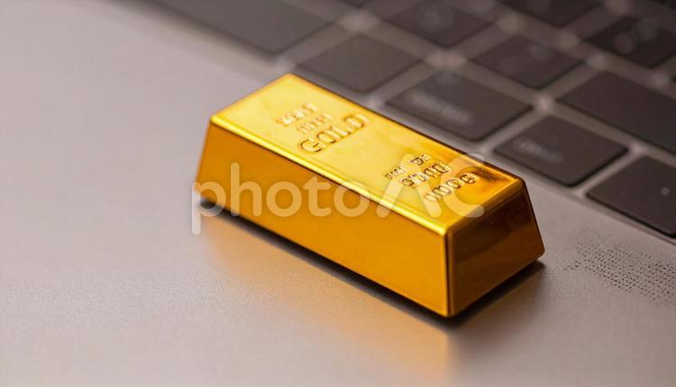 パソコンに置かれた金の延べ棒のミニチュア 金,ゴールド,先物の写真素材