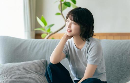 リビングのソファに座る笑顔の女性 リビングのソファに座る笑顔の女性の写真