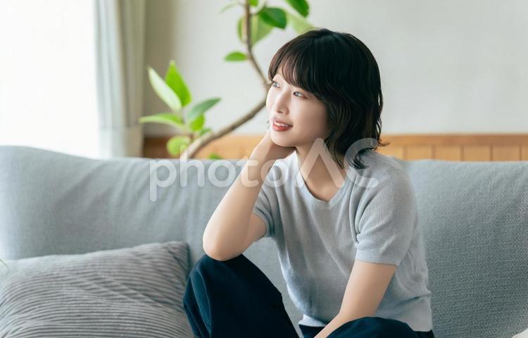 リビングのソファに座る笑顔の女性 女性,ソファ,微笑むの写真素材