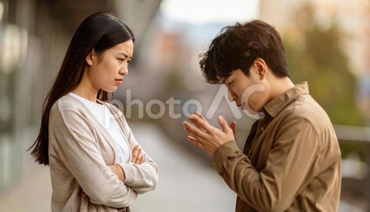 怒って腕組をする女性に頭を下げて謝る男性 喧嘩,カップル,仲直りの写真素材