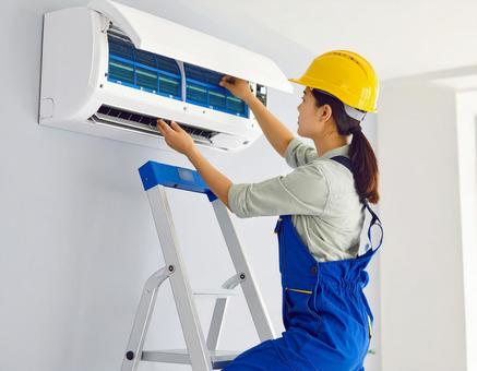 エアコン室内機を修理する女性技術者 エアコン室内機を修理する女性技術者の写真