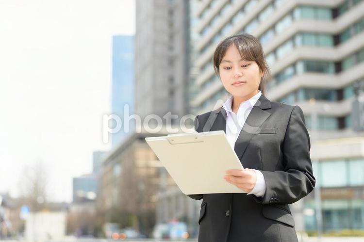 屋外でバインダーを持つスーツの女性 日本人,女性,新入社員の写真素材