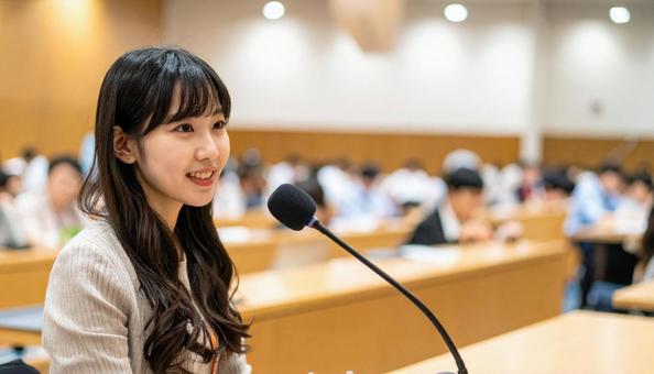 会議で発言する若い日本人女性の写真