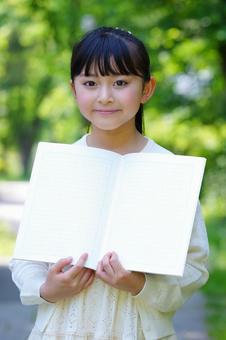 公園でノートを開いて立つ女の子 子ども,女の子,小学生の写真素材