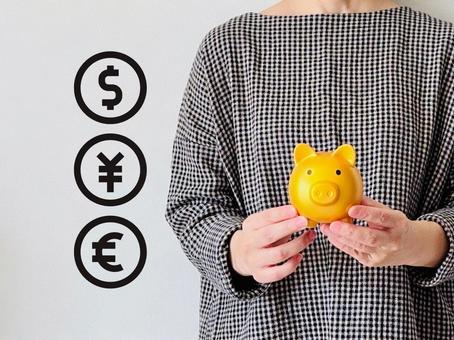 貯金・外貨預金をする女性 貯金・外貨預金をする女性 女性,貯金箱,通貨の写真素材