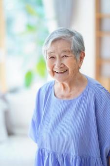 カメラ目線で笑う青い服のおばあちゃん 女性,微笑む,笑顔の写真素材