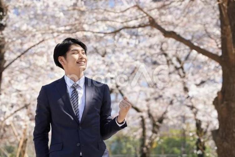桜を背景にガッツポーズをするビジネスマン ビジネスマン,男性,笑顔の写真素材