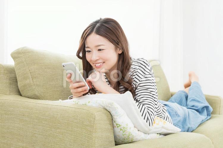 ソファーでスマホを使う女性　 スマートフォン,検索,調べるの写真素材