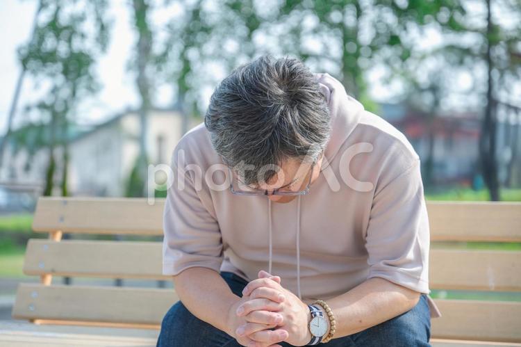 公園のベンチで落ちこむ男性 男性,中年男性,眼鏡の写真素材