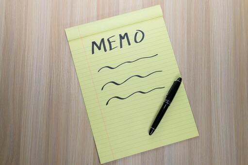 木目調のデスクに置かれたイエローのメモ帳 メモ,ノート,コピースペースの写真素材