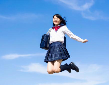 青空と高くジャンプする女子生徒 青空と高くジャンプする女子生徒の写真