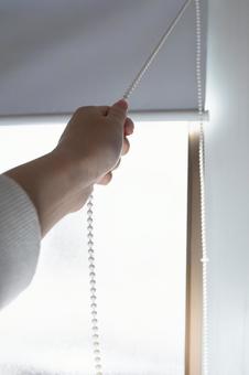 窓のロールスクリーンを開ける 窓のロールスクリーンを開ける ロールスクリーン,ブラインダー,ロールカーテンの写真素材