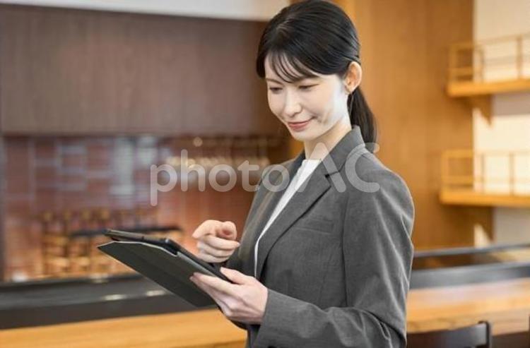 飲食店でタブレットを見るスーツを着た女性 飲食店,女性,スーツの写真素材