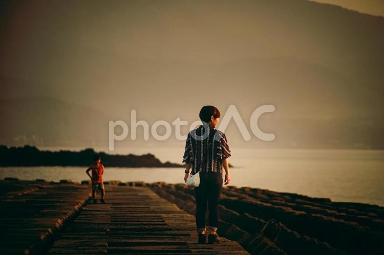 ＜素材＞堤防から夕暮れの海を眺める親子 家族,親子,女性の写真素材
