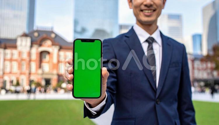 携帯画面を見せて笑うビジネスマン スマートフォン,都市,高層ビルの写真素材