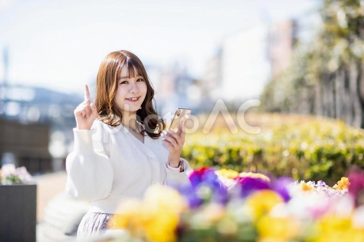 スマホを持って笑顔で指さしする女性 女性,スマホ,電話の写真素材