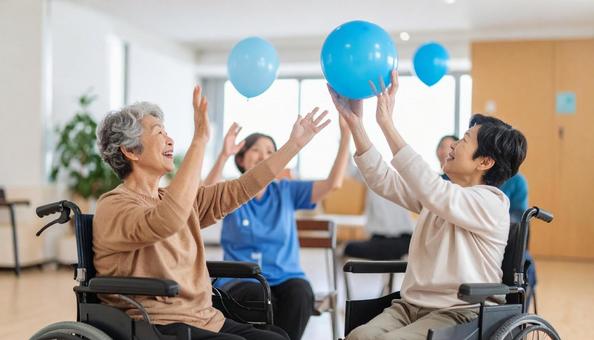 椅子に座り楽しそうに風船バレーをする患者 椅子に座り楽しそうに風船バレーをする患者の写真