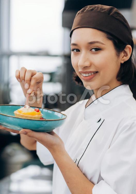 出来上がったデザートを見せるカメラ目線の女性パティシエ キュイジーヌ,キッチン,厨房の写真素材