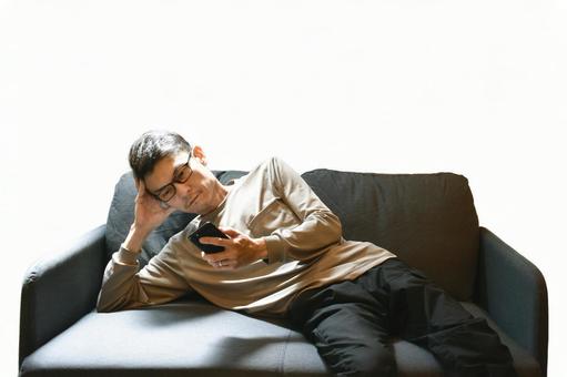 寝そべってスマホを見る男性 くつろぐ,男性,のんびりの写真素材
