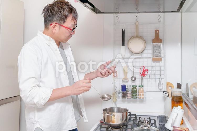 調味料を手に持ち料理する男性 男性,料理,調味料の写真素材