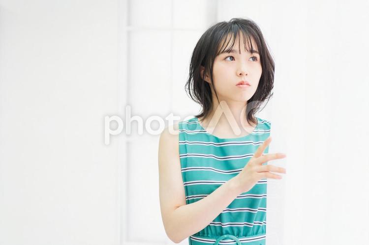 窓際に立ってこちらを見つめている若い女性 窓際,立つ,若いの写真素材