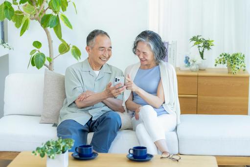 リビングでスマホを見るシニア夫婦 リビングでスマホを見るシニア夫婦 スマホ,シニア,笑顔の写真素材