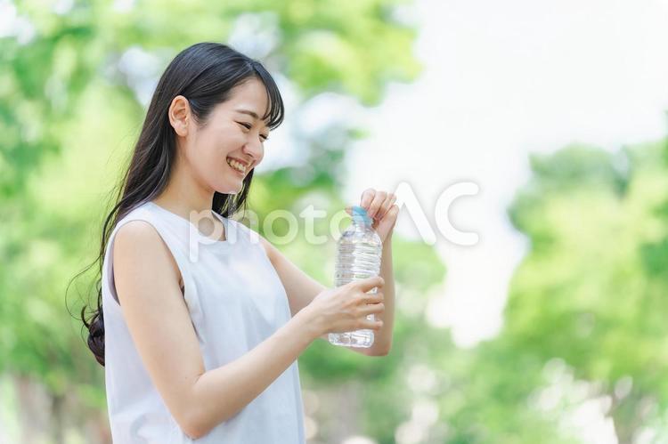 新緑の中で水分補給をする女性 水分補給,水,新緑の写真素材