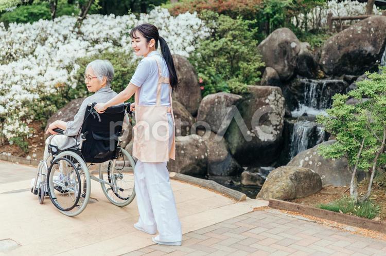 公園を散歩する高齢者女性と女性スタッフ（橋） 介護士,高齢者,看護師の写真素材