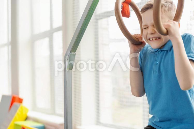 辛そうに吊り輪をする男の子 男の子,吊り輪,辛いの写真素材
