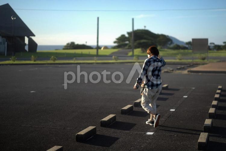 ＜素材＞夏の早朝に公園の駐車場を歩く女性 女性,駐車場,散歩の写真素材