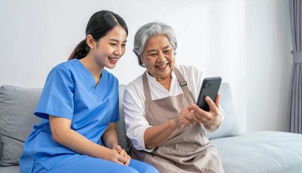 見守り訪問 スマホを使う高齢者とスタッフ 見守り訪問 スマホを使う高齢者とスタッフの写真