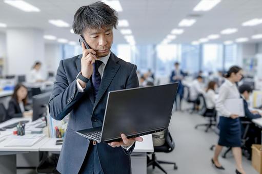 PC見ながら電話するビジネスマン PC見ながら電話するビジネスマン ビジネス,ビジネスマン,男性の写真素材