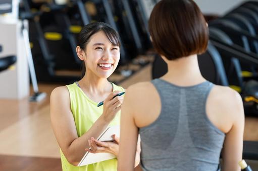 ジムでカウンセリングをする若い女性の写真