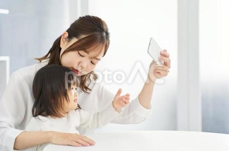 ママとスマホを見る女の子 女性,子供,母親の写真素材