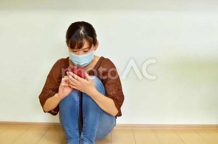 床に座ってスマホを操作する女性2 女性,スマホ,コロナの写真素材