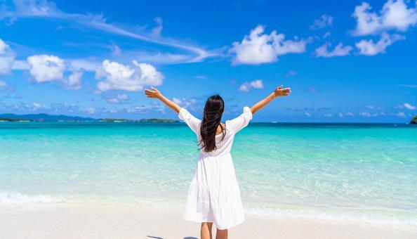 綺麗な海辺で両手を上げて伸びをする女性 綺麗な海辺で両手を上げて伸びをする女性の写真