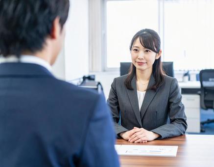 女性上司とその前に立つサラリーマンの部下 女性上司とその前に立つサラリーマンの部下の写真