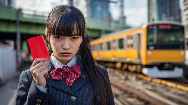 駅でレッドカードを掲げる女子高生 駅でレッドカードを掲げる女子高生の写真