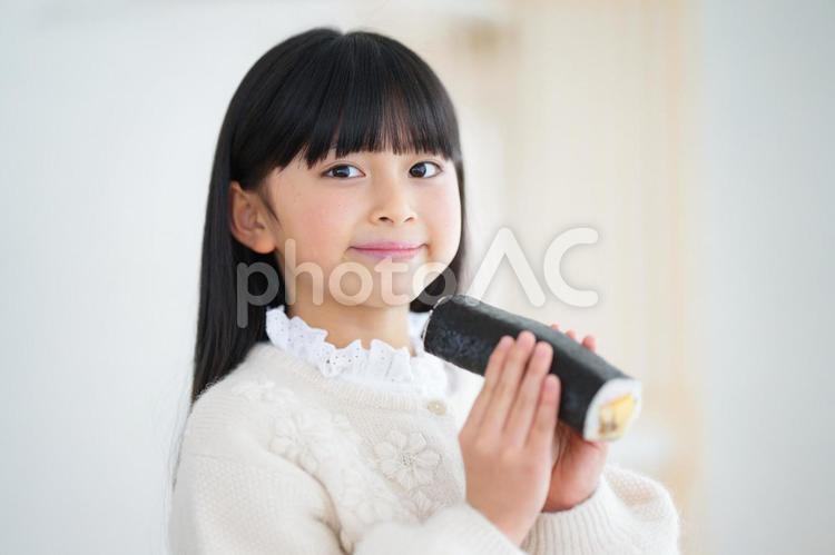 微笑んで恵方巻をもっている女の子 女の子,ロングヘア,長袖の写真素材
